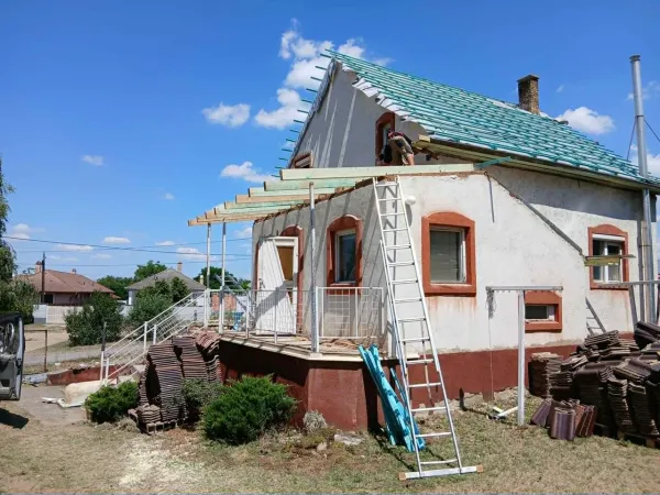 Vidéki ház tetőfelújítása, létra és cserépkupacok az udvaron